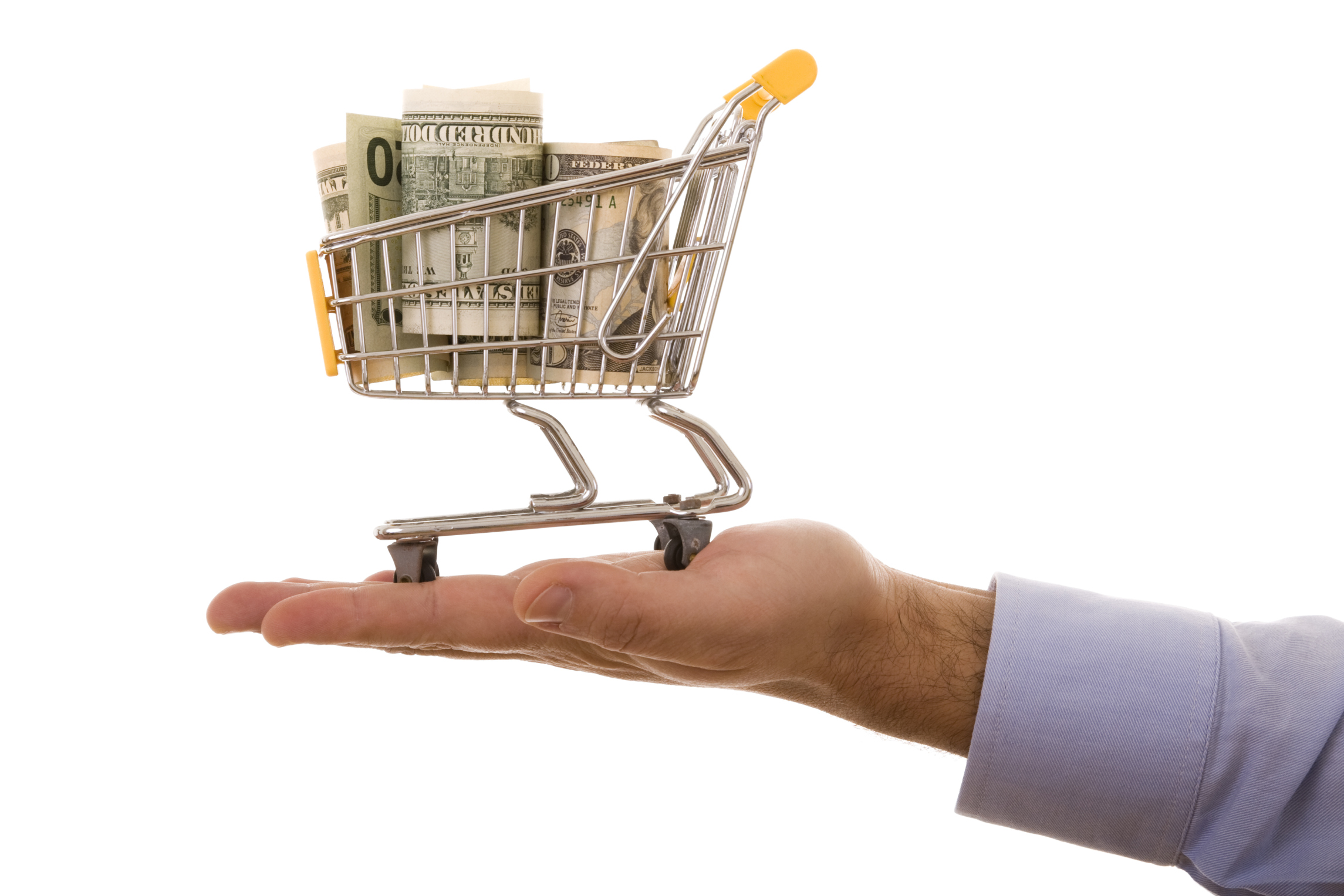 Hand holding a miniature shopping cart full of money