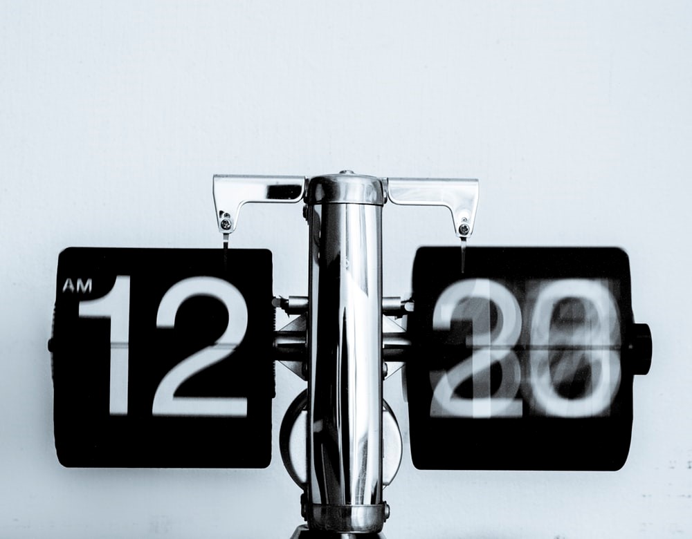 black and white flip clock on a metal apparatus at 12 am with blurring seconds
