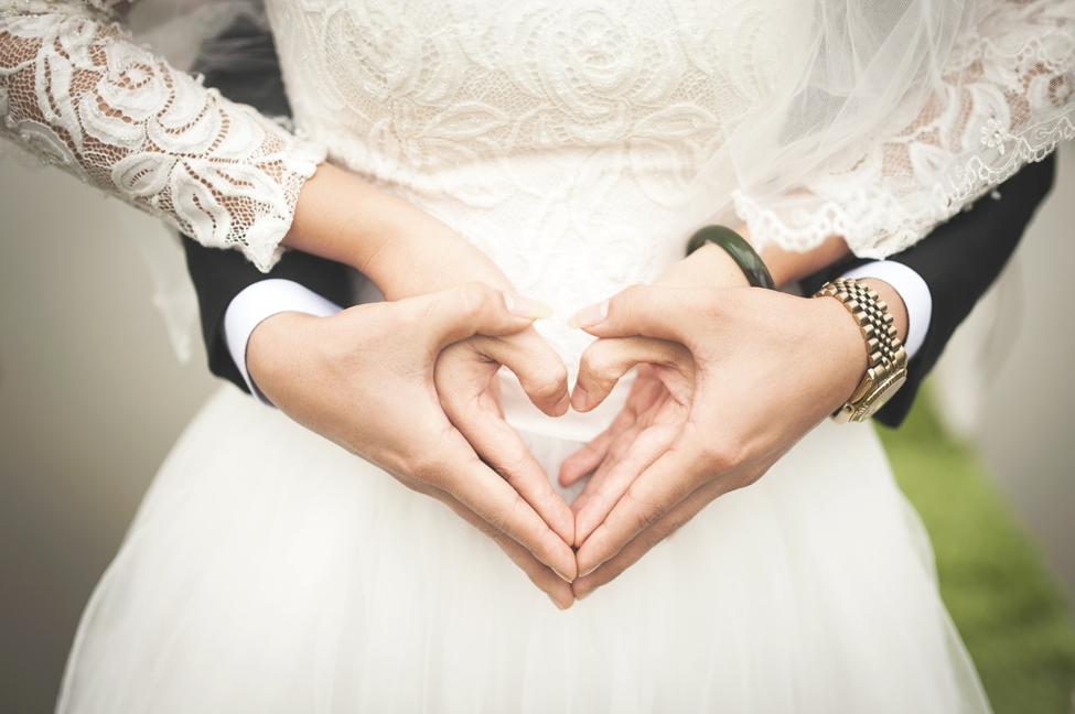 bride and groom forming hearts with hands in front of bride’s wedding dress